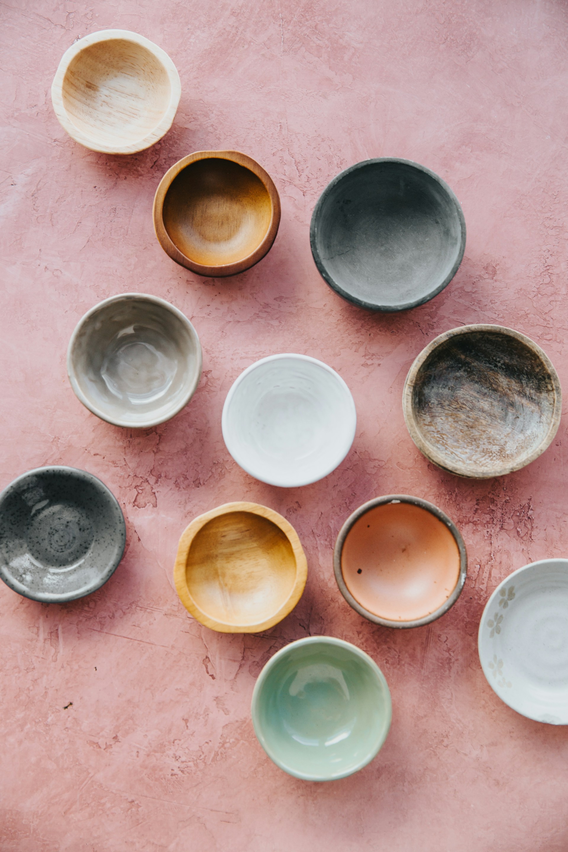 A collection of handmade ceramic bowls and cups in varied glazes, made at Potters Clay